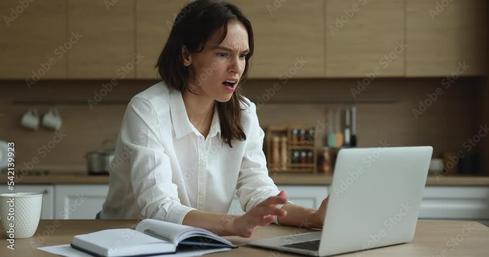 Annoyed woman having problem with laptop, work on computer sit at table feels angry due to broken or discharged device. Unexpected app crash, unsaved data, system error, wifi connection lost concept