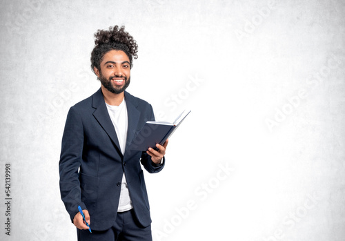 Middle eastern businessman with notebook and pen smiling, copy s