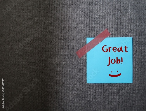 Blue note stick on grey copy space background with words GREAT JOB, concept of positive self talk, praise encouragement note from boss, teacher or clients to express admiration for well done job
