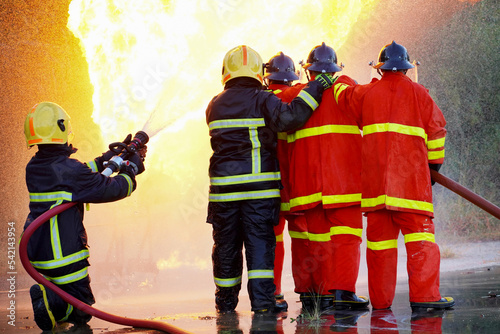 irefighters using Twirl water fog type fire extinguisher to fighting with the fire flame from oil to control fire not to spreading out. Firefighter and industrial safety concept.