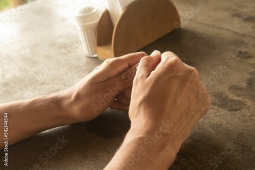 Top view closeup of veiny hands next to a salt and napkins set on a diner table