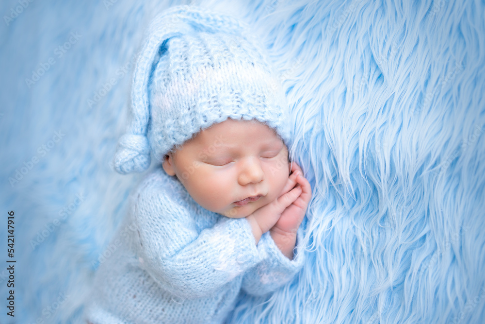 portrait of a newborn baby sleeping sweetly on a blue background with his hands folded under his cheek, healthy baby sleep portrait of a newborn baby sleeping sweetly on a blue background with his hands folded under his cheek, healthy baby sleep