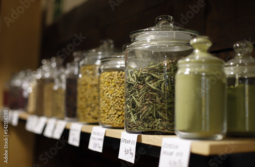 plantas y hierbas en tarro de cristal en estantería de herbolario photo