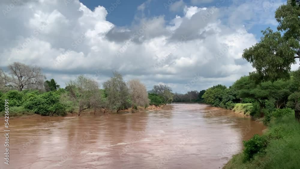 Beautiful shot of Luvuvhu river in flood with trees and blue cloudy sky in Limpopo province, Africa Beautiful shot of Luvuvhu river in flood with trees and blue cloudy sky in Limpopo province, Africa