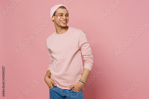 Side view young happy smiling fun gay man wear sweatshirt hat look aside on workspace area mock up isolated on plain pastel light pink color background studio portrait. Lifestyle lgbtq pride concept. photo