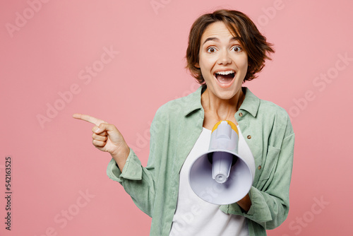 Young woman 20s she wear green shirt white t-shirt hold scream in megaphone announces discounts sale Hurry up isolated on plain pastel light pink background studio portrait. People lifestyle concept