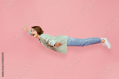 Full body side view young woman she wear green shirt white t-shirt fly fall hover over air hurry up with outstretched hands isolated on plain pastel light pink background. People lifestyle concept photo