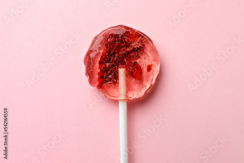 Sweet colorful lollipop with berries on pink background, top view