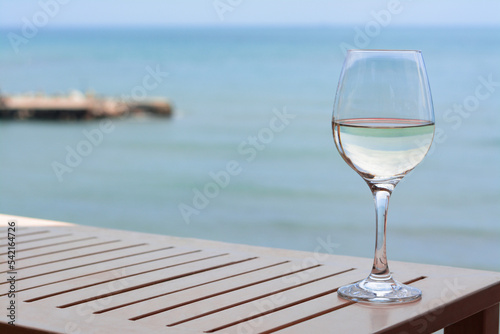 Glass with wine on table near sea. Space for text