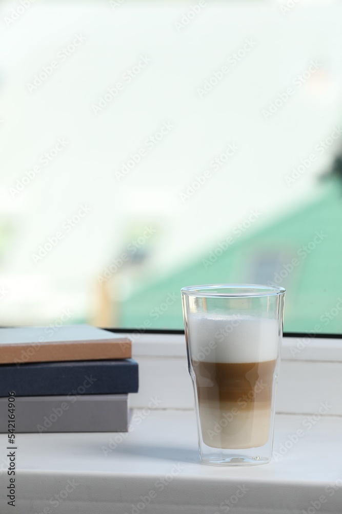 Books and glass with latte on white window sill