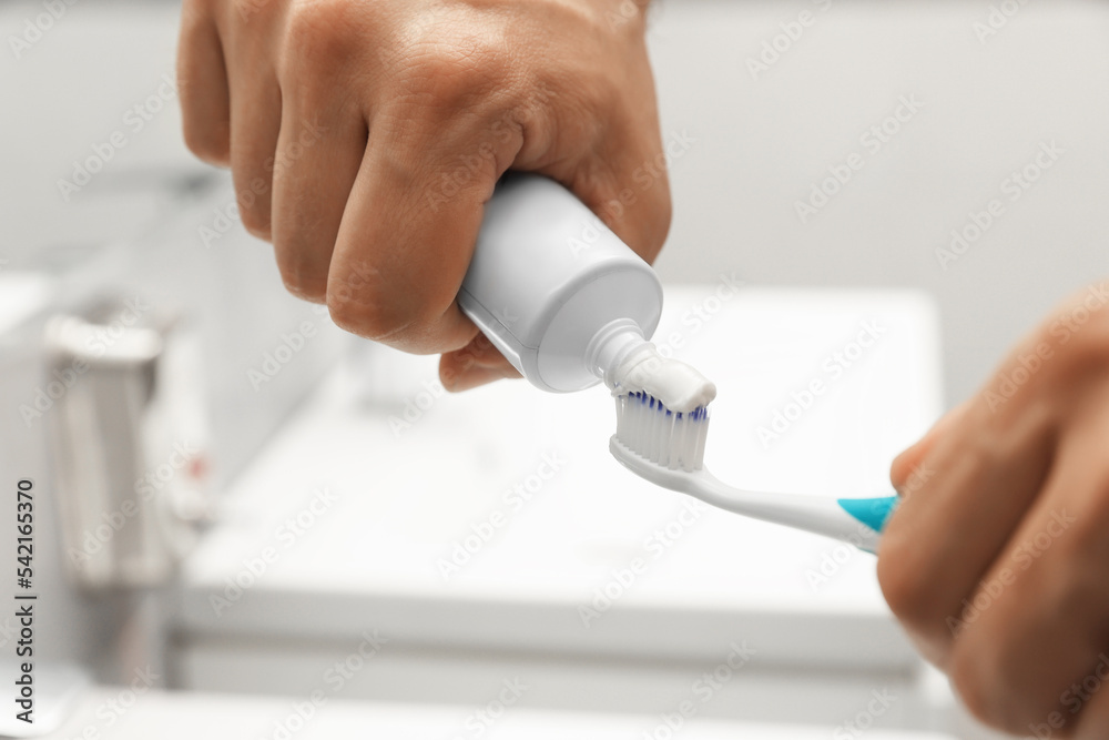 Man applying toothpaste on brush in bathroom, closeup Man applying toothpaste on brush in bathroom, closeup