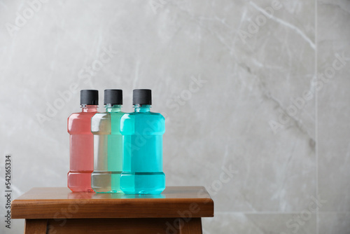 Bottles with mouthwash on wooden table, space for text