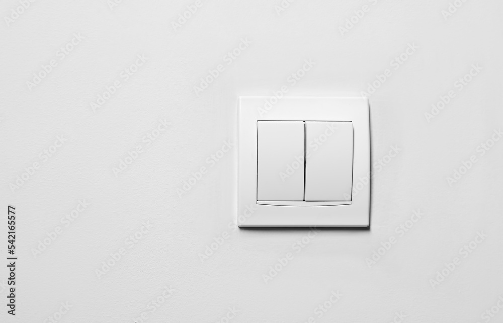 Modern plastic light switch on white wall, space for text Modern plastic light switch on white wall, space for text