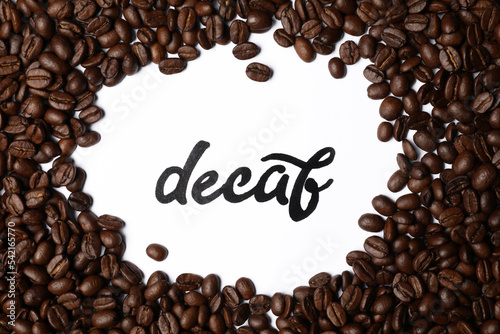 Word Decaf and coffee beans on white background, top view