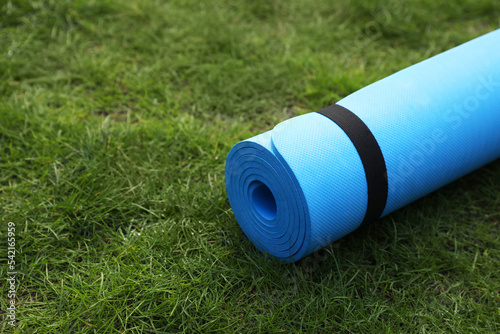 Bright karemat or fitness mat on fresh green grass outdoors, space for text