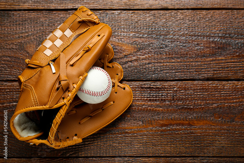 Sticker Leather baseball glove with ball on wooden table, top view