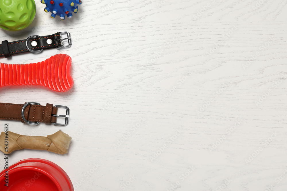Flat lay composition with dog collars and toys on white wooden table. Space for text