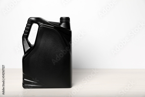 Motor oil in black canister on table against white background, space for text
