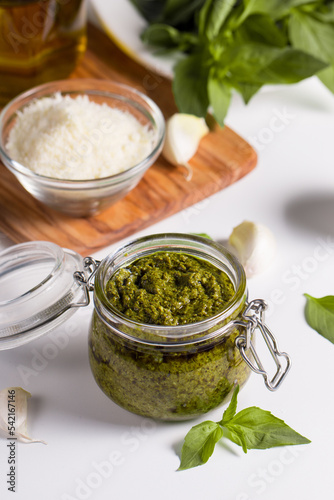 Basil pesto sauce in a jar. Ingredients for cooking, cheese, parmesan, garlic, olive oil. 