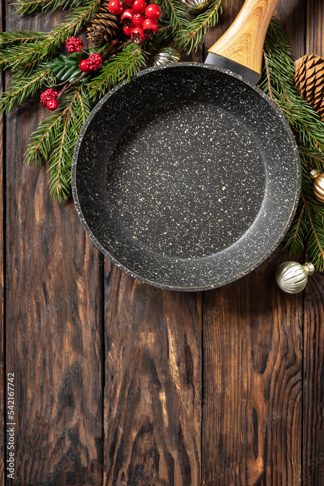 Empty cooking frying pan with tablecloth, Christmas tree and decor on wooden background. Flat mock up for design. View from above. Copy space. Empty cooking frying pan with tablecloth, Christmas tree and decor on wooden background. Flat mock up for design. View from above. Copy space.
