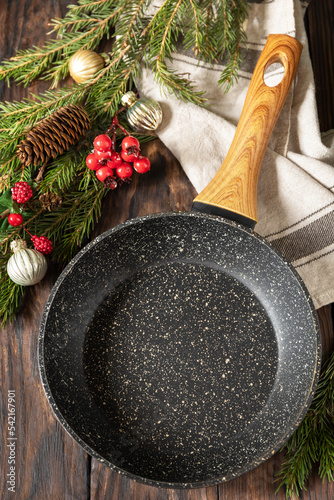 Empty cooking frying pan, Christmas tree and decor on wooden background.