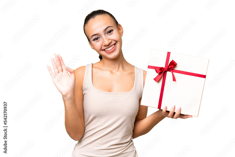 Young Arab woman holding a gift over isolated background saluting with hand with happy expression Young Arab woman holding a gift over isolated background saluting with hand with happy expression