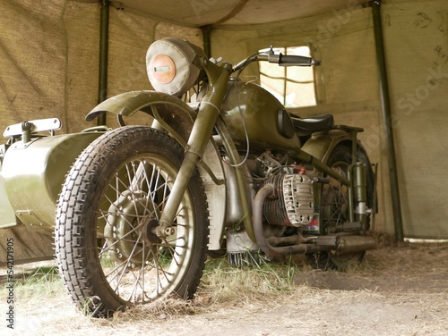 A military motorcycle with a sidecar under an awning. Military camouflage motor vehicles of the Second World War.