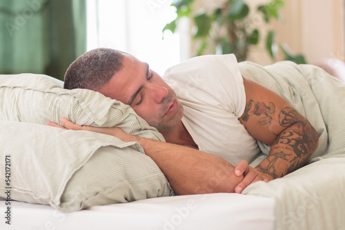 Fotografia Carefree man sleeping on his side in bed in morning