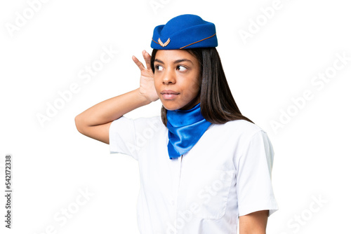 Airplane stewardess African american woman over isolated background listening to something by putting hand on the ear