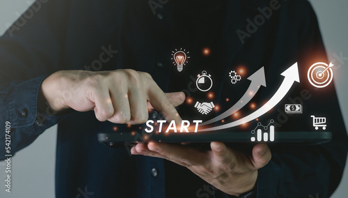 A small to large business startup concept consists of business icons and network connectivity on a modern virtual interface from a digital tablet, a man touching a tablet.