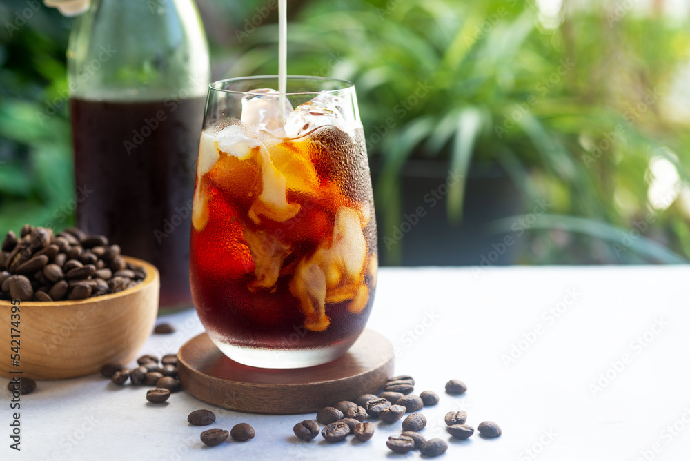 refreshing milk pouring in a glass of homemade cold brew coffee on bright green background refreshing milk pouring in a glass of homemade cold brew coffee on bright green background