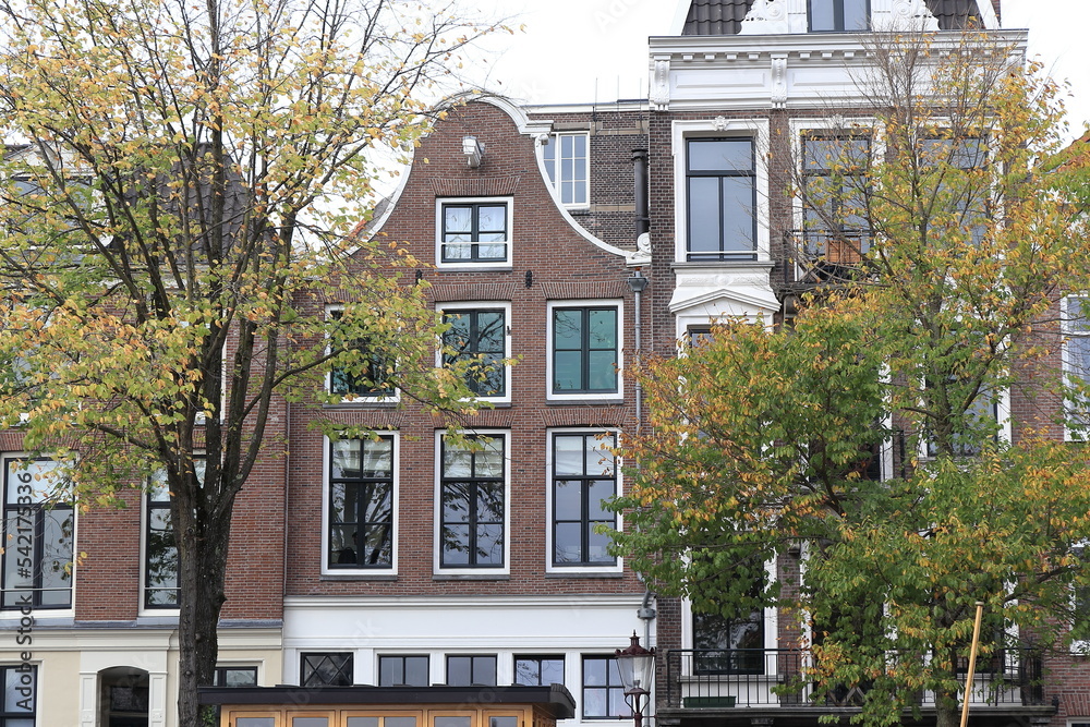Amsterdam Zwanenburgwal Canal Traditional Brick House Facade with Bell Gable and Autumn Trees Close Up, Netherlands