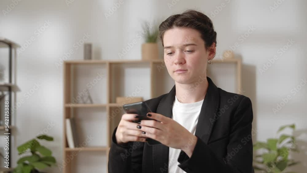Happy businesswoman sit at workplace in modern home office room using smartphone Happy businesswoman sit at workplace in modern home office room using smartphone