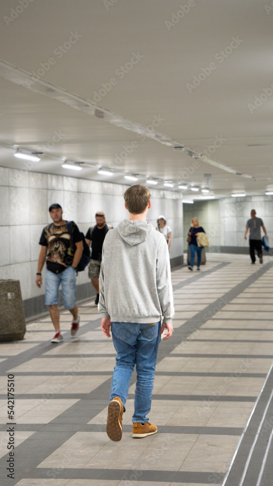 Fototapeta premium Teenager walking alone in tunnel - Stock Photo