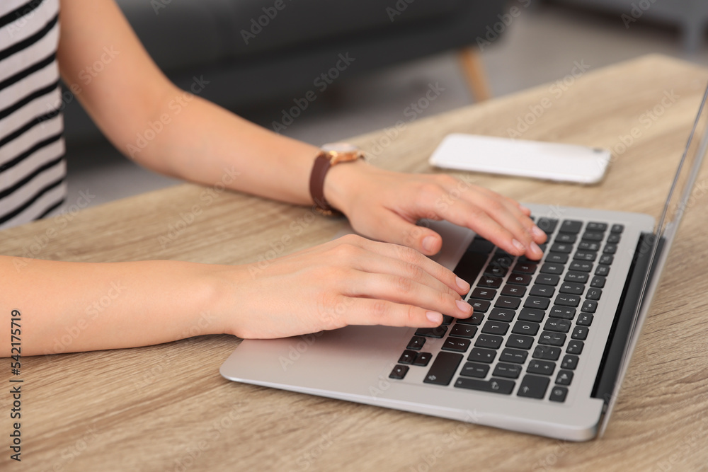 Woman working with laptop at wooden table indoors, closeup Woman working with laptop at wooden table indoors, closeup