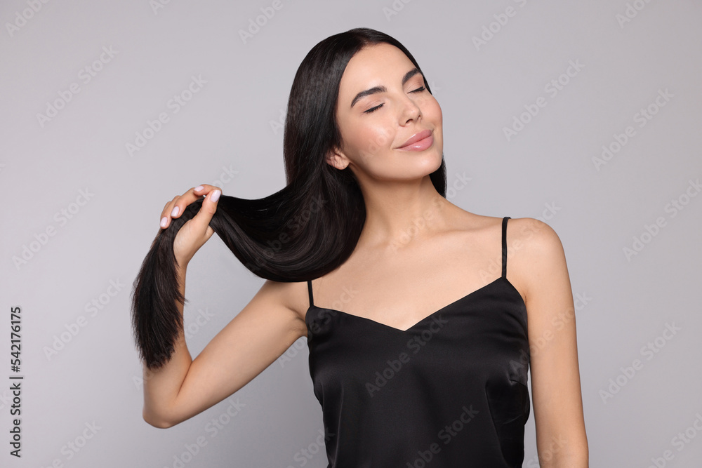 Portrait of beautiful young woman with healthy strong hair on light grey background Portrait of beautiful young woman with healthy strong hair on light grey background