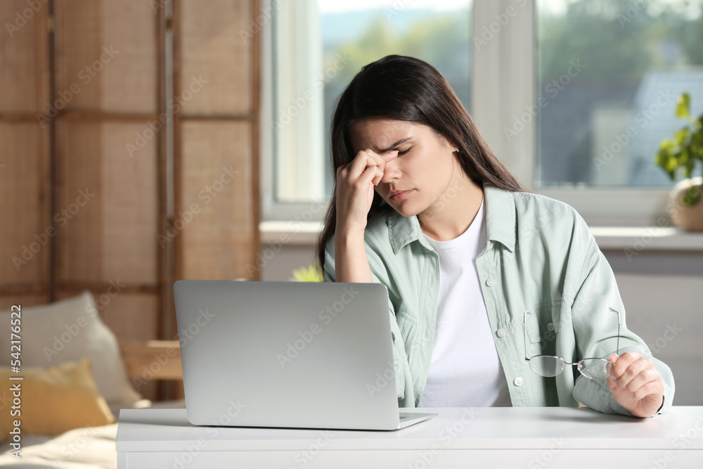 Young woman suffering from eyestrain at desk in office Young woman suffering from eyestrain at desk in office