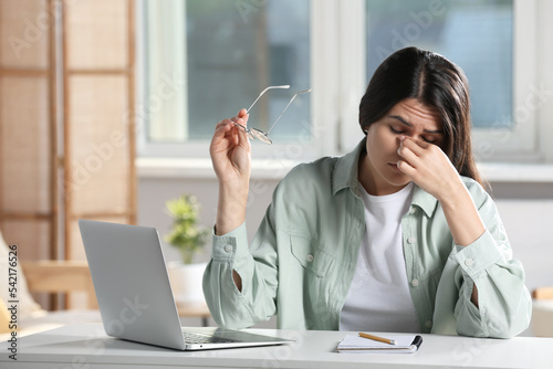 Bild auf Leinwand Young woman suffering from eyestrain at desk in office