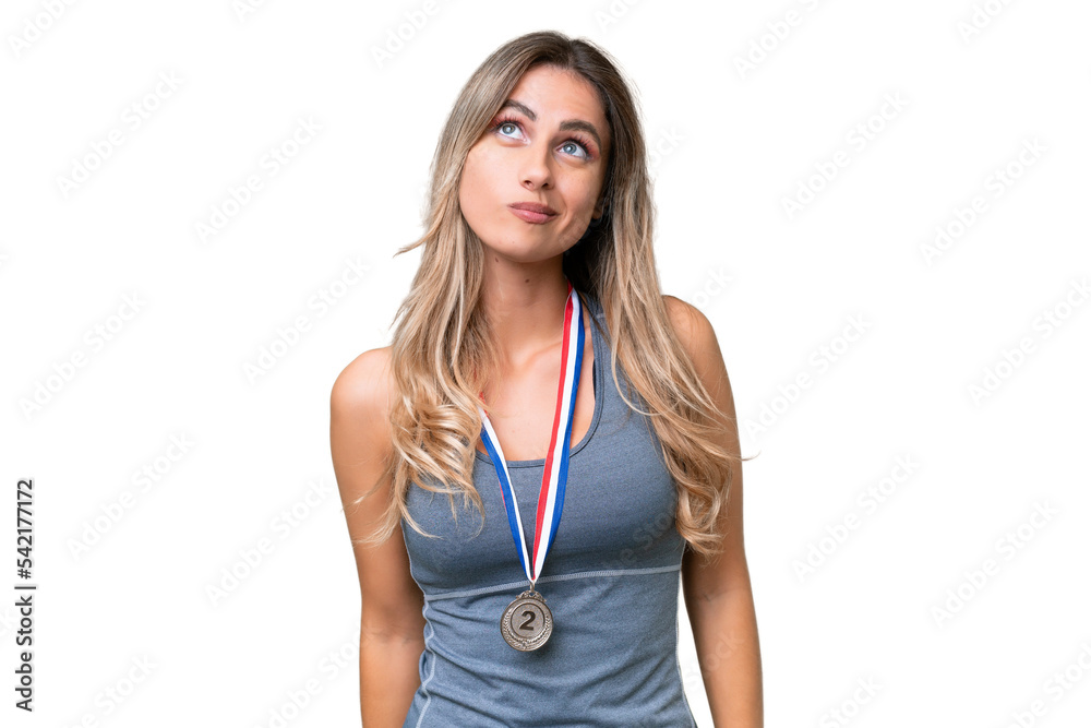 Young pretty sport Uruguayan woman with medals over isolated background and looking up Young pretty sport Uruguayan woman with medals over isolated background and looking up
