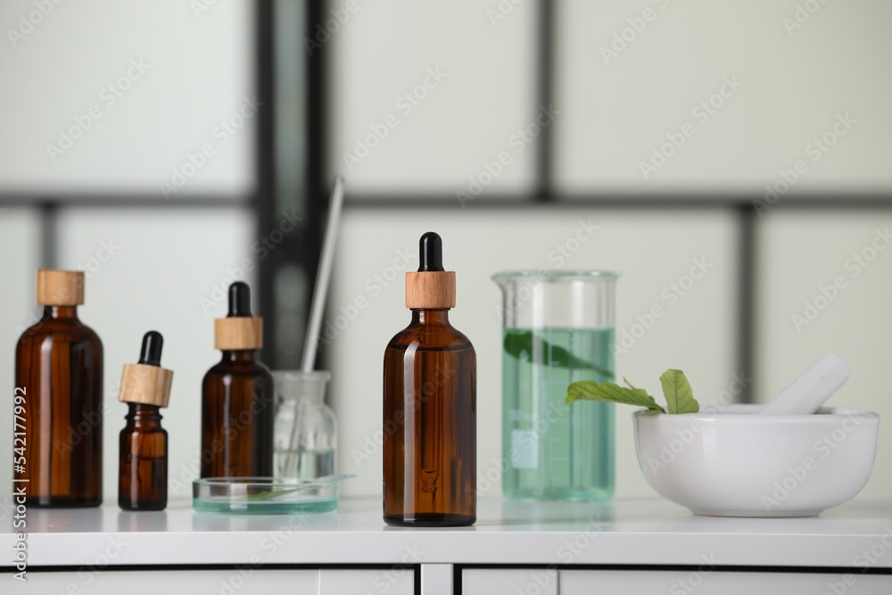 Bottles and glass tubes with leaves on white lab drawer indoors Bottles and glass tubes with leaves on white lab drawer indoors
