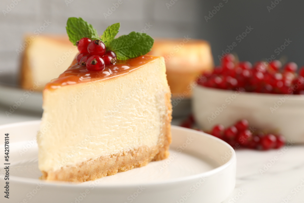 Piece of delicious caramel cheesecake with red currants and mint served on white table, closeup Piece of delicious caramel cheesecake with red currants and mint served on white table, closeup