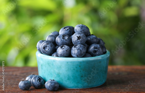 Tasty fresh blueberries on wooden table outdoors, closeup