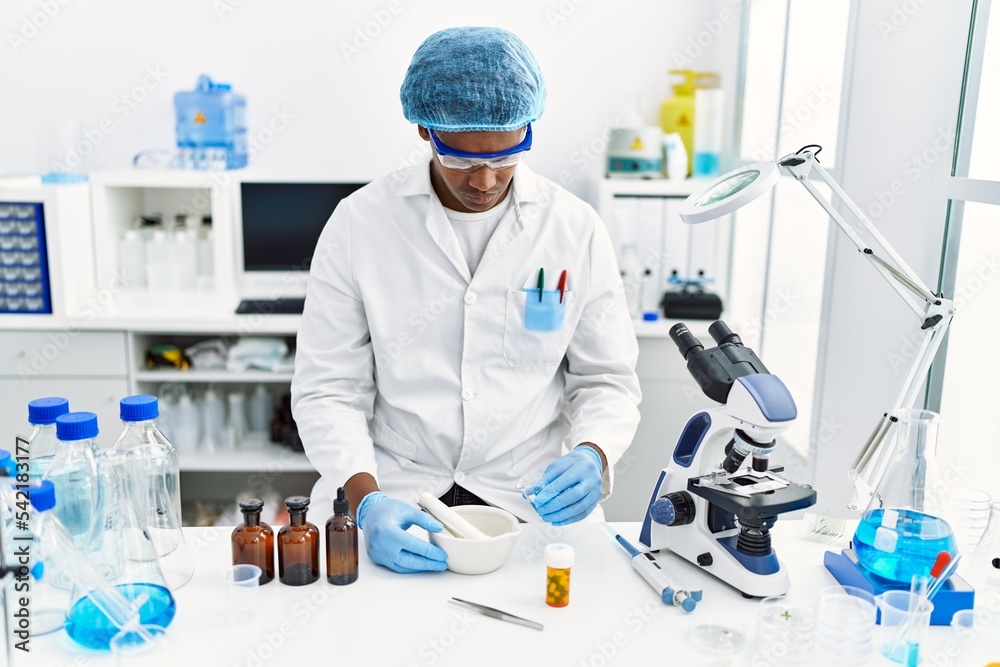 Young south east man wearing scientist uniform making experiment at laboratory Young south east man wearing scientist uniform making experiment at laboratory