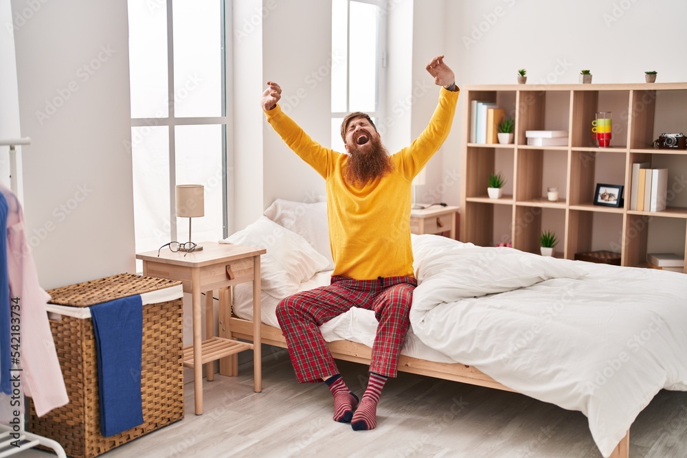 Young redhead man waking up stretching arms yawning at bedroom Young redhead man waking up stretching arms yawning at bedroom