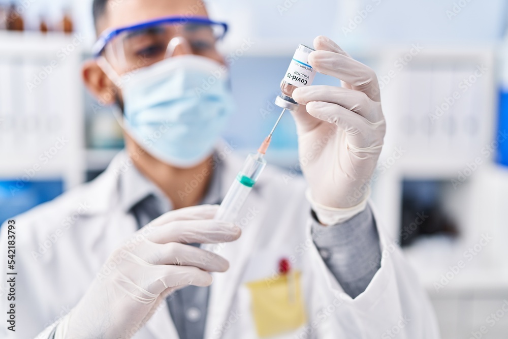 Young hispanic man scientist holding covid vaccine at laboratory Young hispanic man scientist holding covid vaccine at laboratory
