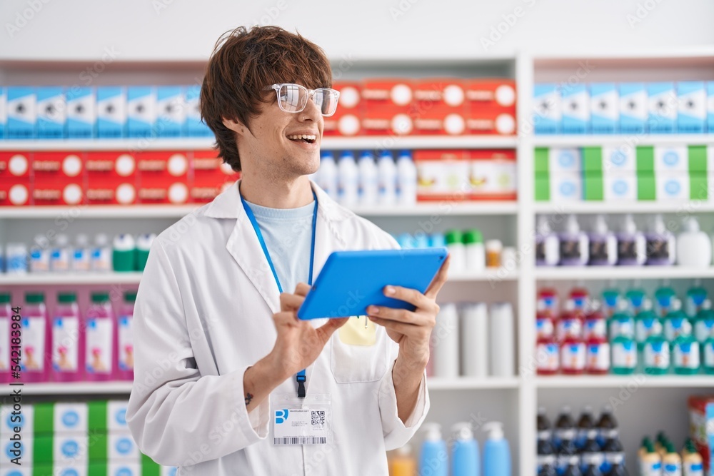 Young blond man pharmacist using touchpad working at pharmacy Young blond man pharmacist using touchpad working at pharmacy