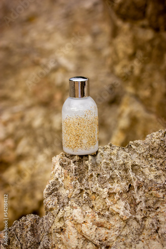 Cosmetics bottle with white natural skin hair care product - soap, shampoo, gel, serum on vertical brown beige rocks background, stone podium. Eco organic cosmetic tube modern still life. Body care.