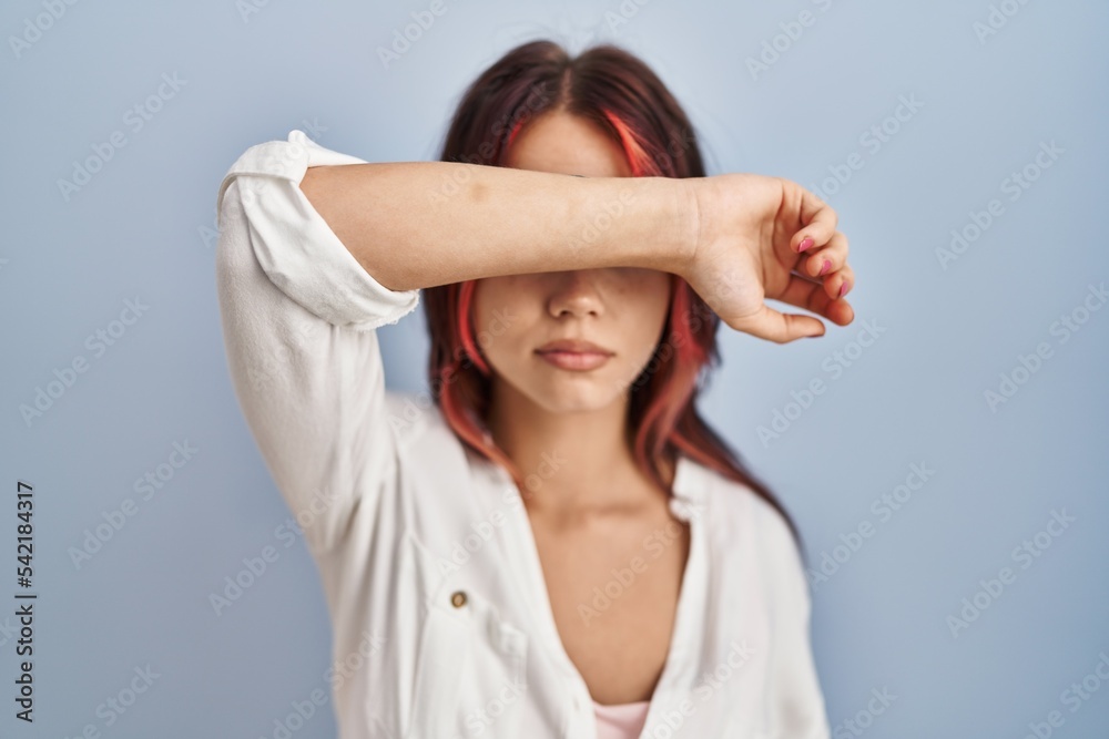 Naklejka premium Young caucasian woman wearing casual white shirt over isolated background covering eyes with arm, looking serious and sad. sightless, hiding and rejection concept