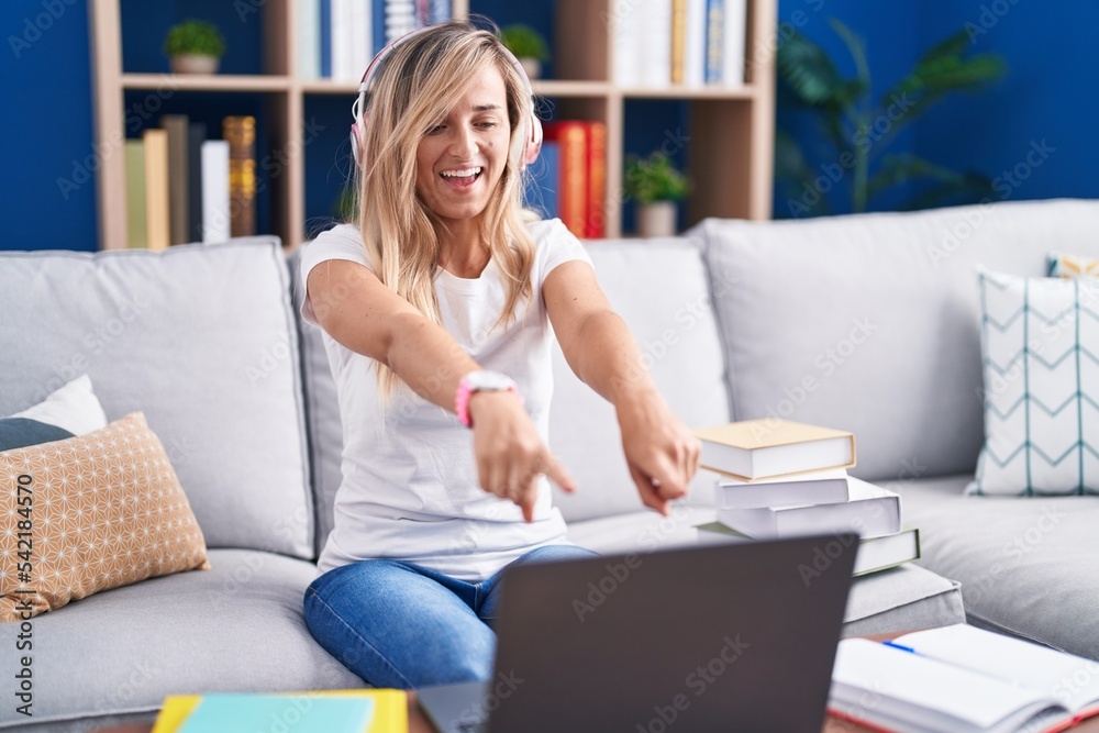 Young blonde woman studying using computer laptop at home pointing to you and the camera with fingers, smiling positive and cheerful Young blonde woman studying using computer laptop at home pointing to you and the camera with fingers, smiling positive and cheerful