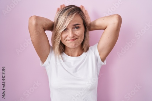 Young blonde woman standing over pink background doing bunny ears gesture with hands palms looking cynical and skeptical. easter rabbit concept.